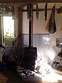 A woodburner in the middle of the image with a patch of sun on the hearth and a window to the left of the chimney. Towels drying above.