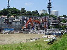 A school building being demolished in Tama New Town, Tokyo due to low enrolment, showing the steel frame used during its construction inside the remaining piece of outer wall. Duo Mo niyutaundeShao Zi Hua niBan iJie Ti sarerupurehabuXiao Yadoru 150710.JPG