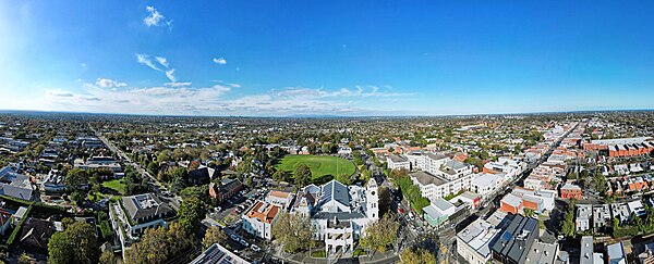 Aerial panorama of Malvern Town Hall intersected by Glenferrie Road and High Street. April 2023.