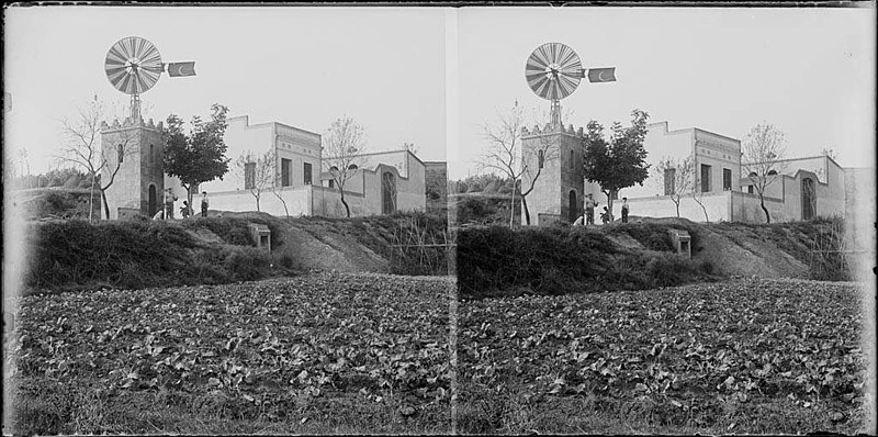 File:Camps de conreu amb un grup d'homes al costat d'una torre amb un molí de vent i alguns edificis (AFCEC BORDAS D 4085).jpeg