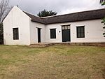 This building was erected in the eighteen-twenties as a dwelling for the Deputy Landdrost. It is in the Cape Dutch style and TT -shaped. The building is one of the oldest dwellings in Clanwilliam. Type of site: House. Current use: Residential.