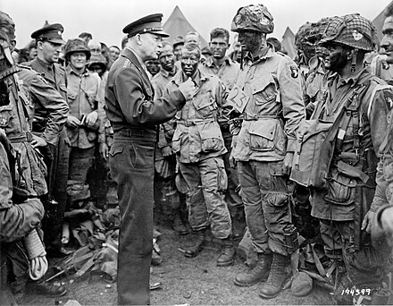Eisenhower speaks with men of the 502nd Parachute Infantry Regiment (PIR), part of the 101st "Screaming Eagles" Airborne Division, on June 5, 1944, the day before the D-Day invasion. The officer Eisenhower is speaking to is First Lieutenant Wallace Strobel.
