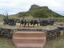 Memorial erected at the site commemorating the valour of the fallen Zulu impi at Isandlwana Hill, which is visible in the background Isandlwanazulumem.JPG