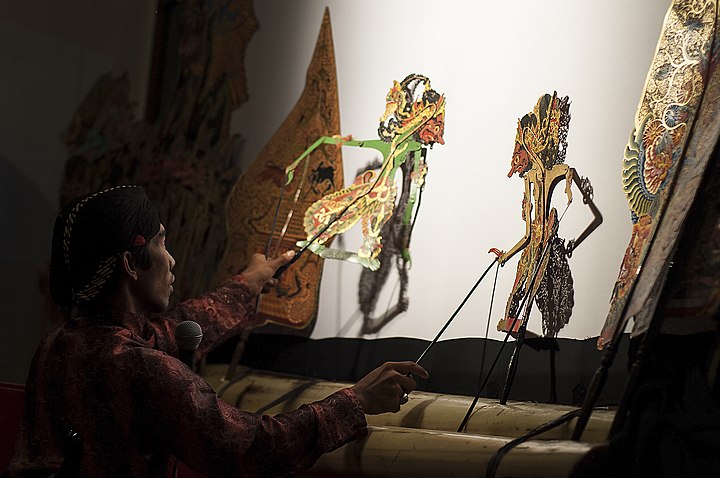 A dalang (puppet master) depicting a fight in a wayang kulit performance