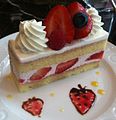 A strawberry layer cake with strawberries in the frosting between the layers and a strawberry garnish