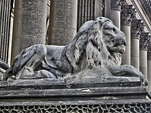 Una estatua de tamaño natural de un león, con la cara erosionada por la intemperie.