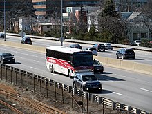 A Framingham Logan Express bus in the line's red livery. All routes but Back Bay use coach-style buses. Logan Express Framingham bus on the Mass Pike in Allston, April 2017.JPG