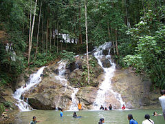 Bathing locals at the foot of a waterfall.