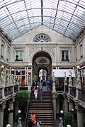 Ampia copertura vetrata sorretta da archi metallici, sovrastante il vasto spazio della galleria centrale, con al centro la sua scala