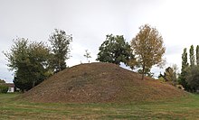 Overblijfselen van de kasteelheuvel van Saint-Cyr, een aarden koepel omringd door enkele bomen.