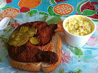 Hot chicken chicken dish from Nashville, Tennessee, US; bone-in chicken pieces, marinated in a water-based blend of seasoning, floured, fried, sauced using a paste with cayenne pepper, served on slices of white bread with pickle chips