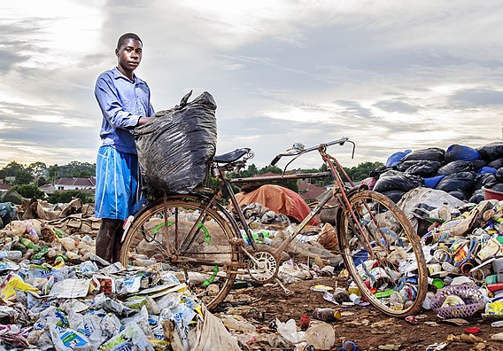 A young man in Uganda who is working in a waste dump. Because of work locations and conditions, there is a high chance of catching disease or injury while working as a waste picker in certain environments.