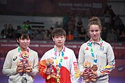 Deutsch: Tischtennis bei den Olympischen Jugend-Sommerspielen 2018: Tag 4, 10. Oktober 2018, Mädchen-Einzel, Siegerehrung - Gold: Yingsha Sun (CHN), Silber: Miu Hirano (JPN), Bronze:Andreea Dragoman (ROU)); Medaillen überreicht durch IOC-Mitglied Ching-kuo Wu (TPE), Maskottchen überreicht durch ITTF-Vize-Präsident Masahiro Maehara (JPN) English: Fencing at the 2018 Summer Youth Olympics at 10 October 2018 – Girls' single medail ceremony – Gold: Yingsha Sun (CHN), Silber: Miu Hirano (JPN), Bronze:Andreea Dragoman (ROU)); Medal presenter: IOC member Ching-kuo Wu (TPE), Mascot presenter: Vice-President Executive of the ITTF Masahiro Maehara (JPN)