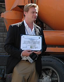 Photographie d'un homme souriant en train de porter un certificat.