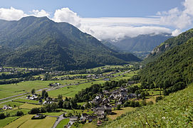 Foto van een landschap met een vallei omringd door beboste bergen.