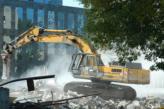 Excavator (a type of heavy equipment commonly used at construction sites and roadworks) demolishing the remnants of the pre-war Postal Train 0880Stati