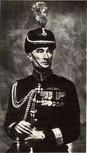 Formal portrait of man in dark-coloured dress uniform and headgear with braid and medals