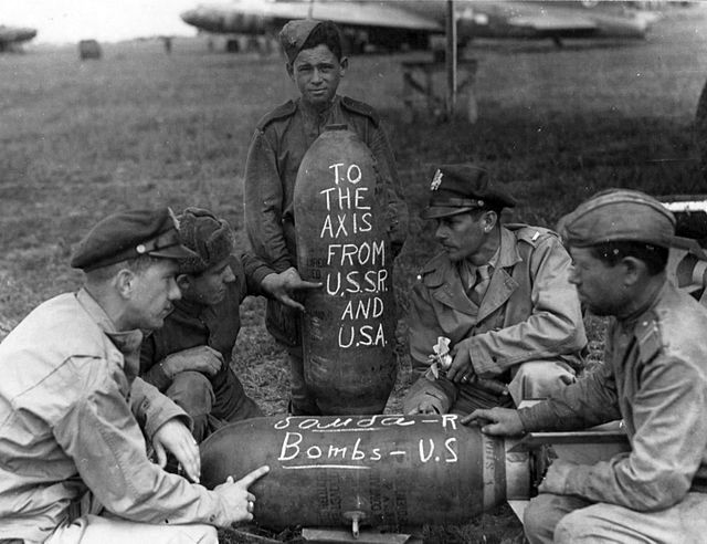 American and Soviet military personnel write messages on aerial bombs