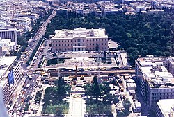 Veduta aerea della Piazza Sintagma di Atene con il palazzo del Parlamento immerso nel verde dei Giardini Nazionali e il lungo rettifilo di viale Regina Sofia sul suo fianco (a sinistra nella foto)