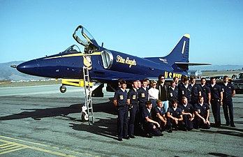 Besättningen för Blue Angels anno 1983 tillsammans med John Travolta och Olivia Newton-John med en A-4 Skyhawk i bakgrunden.