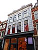 Winkelwoonhuis met voorgevel uit de 19e eeuw in neoclassicistische stijl, in opzet mogelijk ouder.