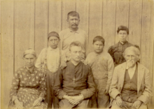 Formal photograph of an older Eliza and Mathias Splitlog, seated with a young William Ketcham wearing a large crucifix. Behind them are two Splitlogs of the younger generation, and two grandsons.