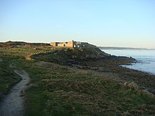 Vue d'un fort construit sur un petit promontoire rocheux, surplombant la mer.