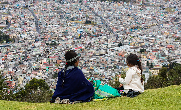 Indigenous people peeling maize while overlooking Quito from El Panecillo, Ecuador.