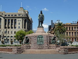 An impressive monument. A statue of Kruger stands on a tall plinth; he is wearing his top hat. Each of the plinth's four sides has a statue of a crouching Boer next to it.