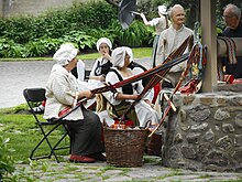 Des artisanes en costume d'époque réalisent des ceintures fléchées à l'extérieur.