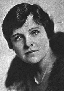 Head and shoulders of a woman with short, dark hair, wearing a fur collar