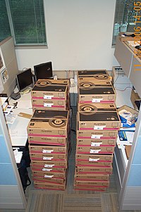 Boxes of monitors stacked in a cubicle.