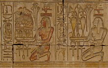 Relief, das zwei kniende Personen zeigt, die Tabletts mit Pflanzen, Krügen mit Flüssigkeiten und Lebensmitteln tragen