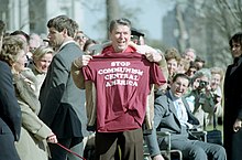 President Ronald Reagan holding a "Stop Communism in Central America" t-shirt on the South Lawn of the White House in March 1986 President Ronald Reagan holding a Stop Communism T-Shirt.jpg