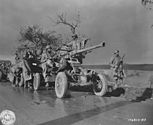 Members of Battery A, 452nd AA stand by and check their equipment while the convoy takes a break. November 9, 1944. SC 196212-A-S - Members of an artillery unit stand by and check their equipment while convoy takes a break. E.T.O., 9 November, 1944. (51975122956).jpg