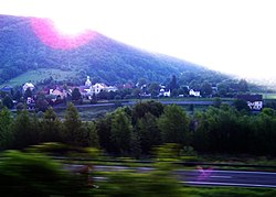 Těchlovice s věžičkou farního kostela Stětí sv. Jana Křtitele (pohled z jedoucího vlaku přes řeku Labe)