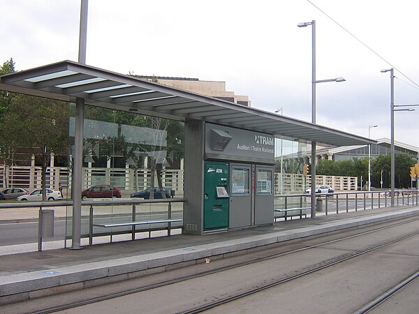 View of one of the railway platforms, the tracks and one of the shelters of Auditori – Teatre Nacional tram stop. Several facilities such as the ticke