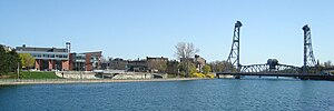 Downtown Welland, with the Waterway in the foreground, the Civic Square on the left, and the historic vertical lift East Main Street Bridge (Bridge #13) on the right. Welland Canal downtown.jpg