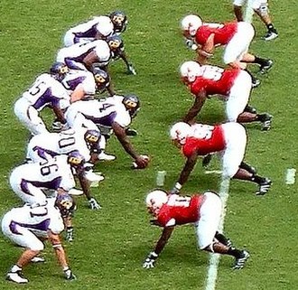 The four defensive linemen (in red) have their hands on the ground in a "three point stance"