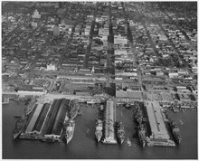 Aerial photograph of piers at headquarters and at U.S. Naval Repair Base during loading operations showing nine Army transport ships docked at the commercial wharfs at San Diego, California. (National Archives and Records Administration) (Aerial photograph of piers at headquarters and at U. S. Naval Repair Base during loading operations showing nine... - NARA - 295638.tif