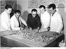 Architects examining a model (urban planning) from a bird's-eye view, Rostock, 1955 Bundesarchiv Bild 183-28849-0005, Rostock, Architekten bei der Stadtplanung.jpg