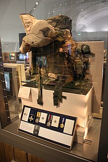 The damaged backpack worn by Croucher along with some of his medals Croucher, Matt (GC) backpack.JPG