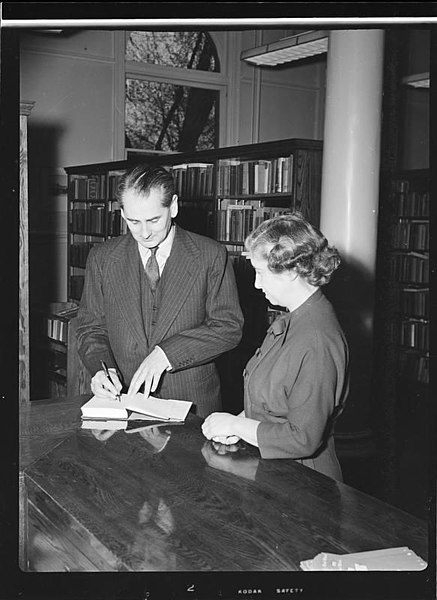 Nicholas Monsarrat signing a copy of The Story of Esther Costello as Dorothy Shoemaker watches.