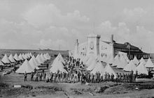 Recruits gathered at the Regina barracks, 1918, showing the large riding school in the background Royal North-West Mounted Police Barracks, ca. 1904 - 1925.jpg