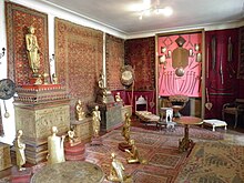 Pièce décorée de tapis aux murs et sur le sol, avec statues de bouddhas