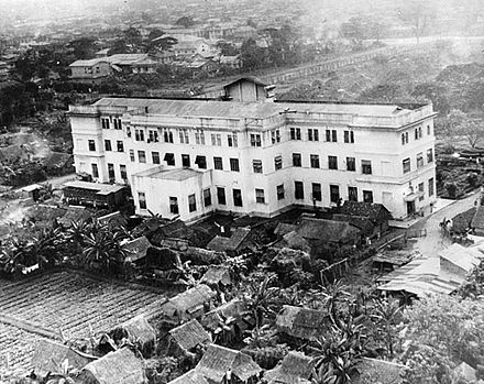 One of the principal buildings housing internees at the Santo Tomas Internment Camp was the Education building (now the UST Hospital). Shanties and vegetable gardens can be seen near the building and the wall of the university compound is in the background.