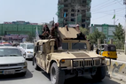 Taliban soldiers ride a beige Humvee through the streets of Kabul