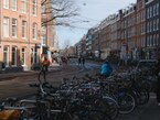 Amsterdam 2023 - a view through the city street Albert Cuypstraat in De Pijp district with sunlight and shadows on the house facades and a lot of parked bicycles at the sidewalk - free download photo in Dutch street photography by Fons Heijnsbroek, Netherlands