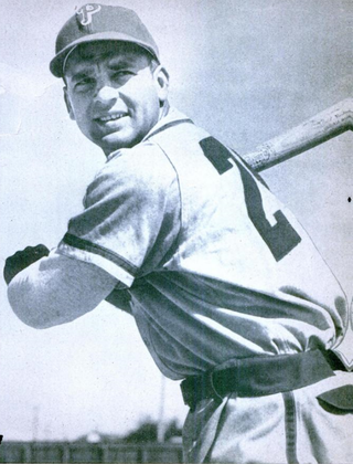 A black-and-white photograph of a man wearing a white baseball uniform and cap with "P" on the face