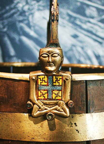 The so-called "Buddha bucket" (Buddha-bøtte), a brass and cloisonné enamel ornament of a bucket (pail) handle in the shape of a figure sitting with cr